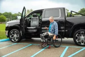 Wheelchair user transferring into a driver seat from a black accessible truck
